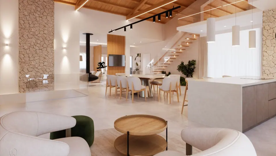 Open space sotto un tetto con travi in legno, parete in pietra, scala sospesa e lungo tavolo da pranzo con sedute chiare