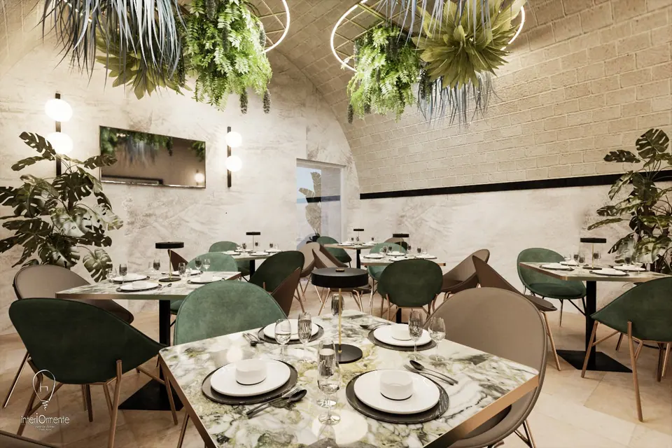 Sala ristorante con volta in pietra, piante sospese, tavoli in marmo verde e sedie in velluto verde e tortora