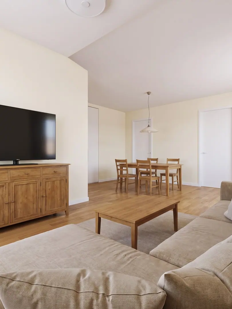 Simulazione con AI del soggiorno prima del progetto, con pareti color crema, credenza in legno sotto il televisore e tavolo da pranzo con sedie semplici