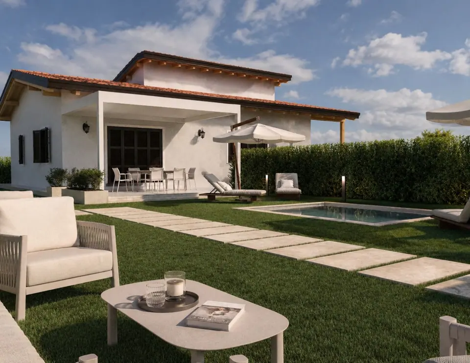 Villa bianca con portico e ombrellone, prato con camminamento in pietra, piscina e salotto da esterno